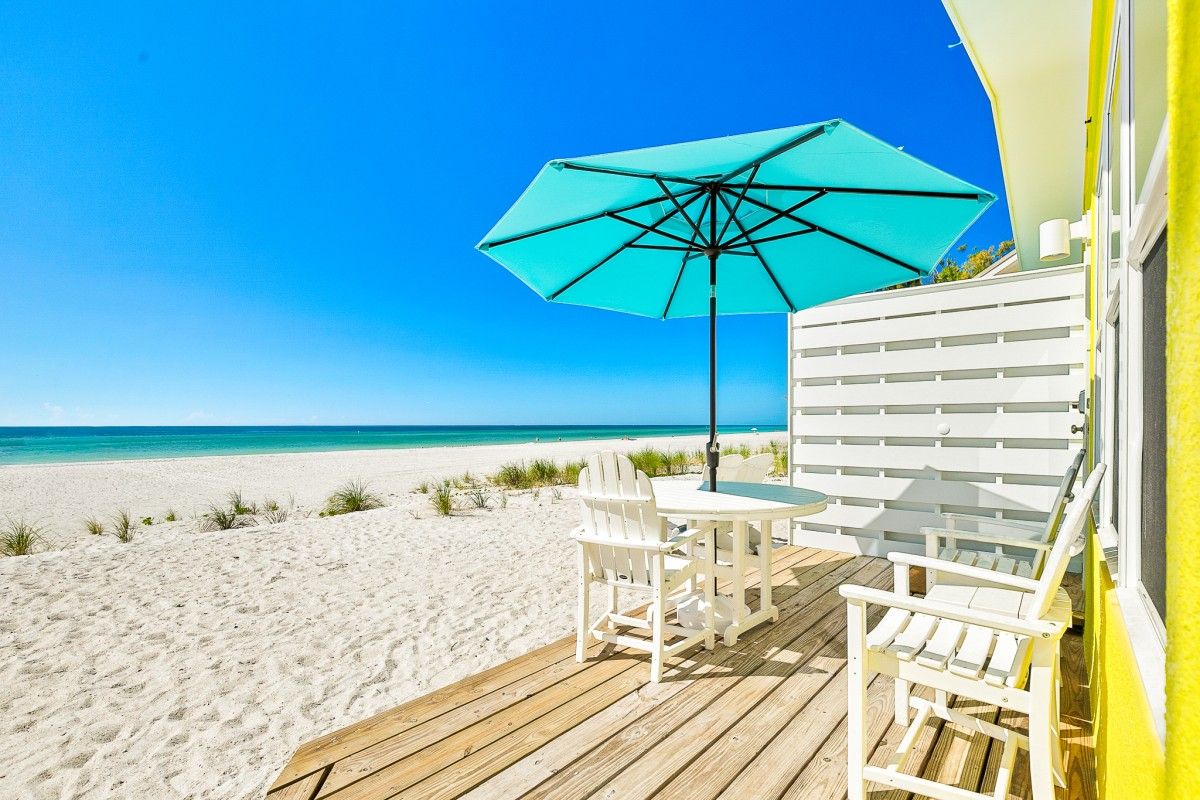 view of bright blue ocean and white sand beach from porch of beachfront rental