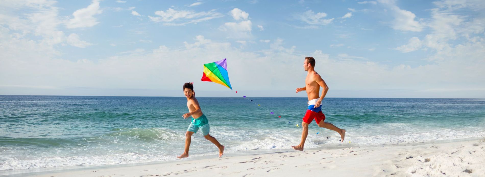 father and son fly kite on beach